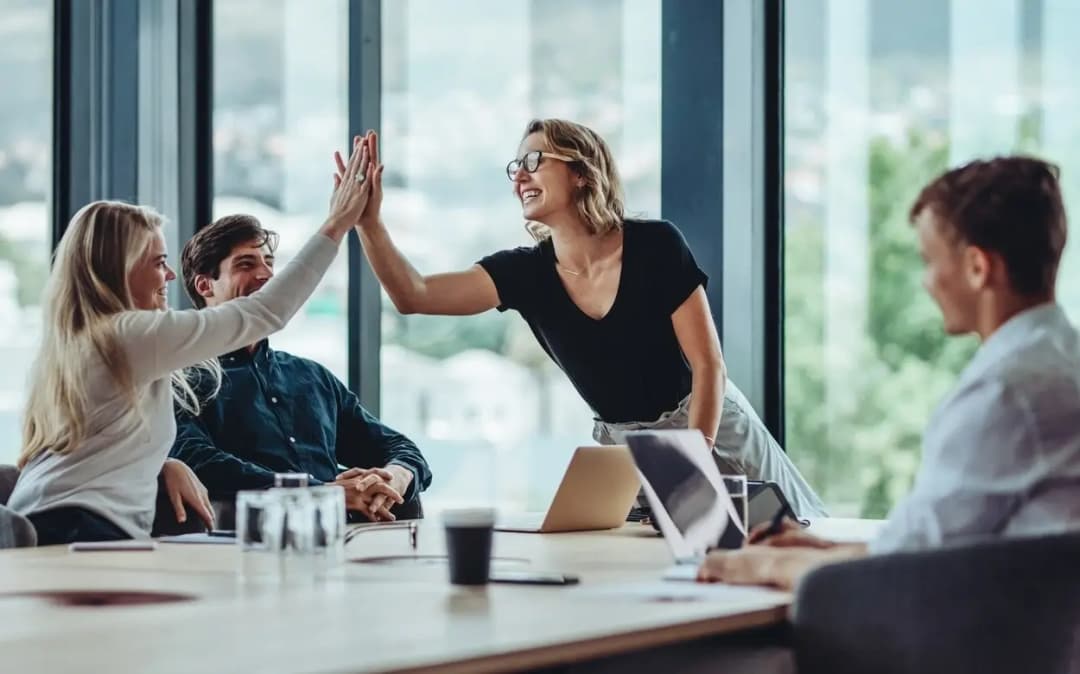 Co-workers high-five at a conference table