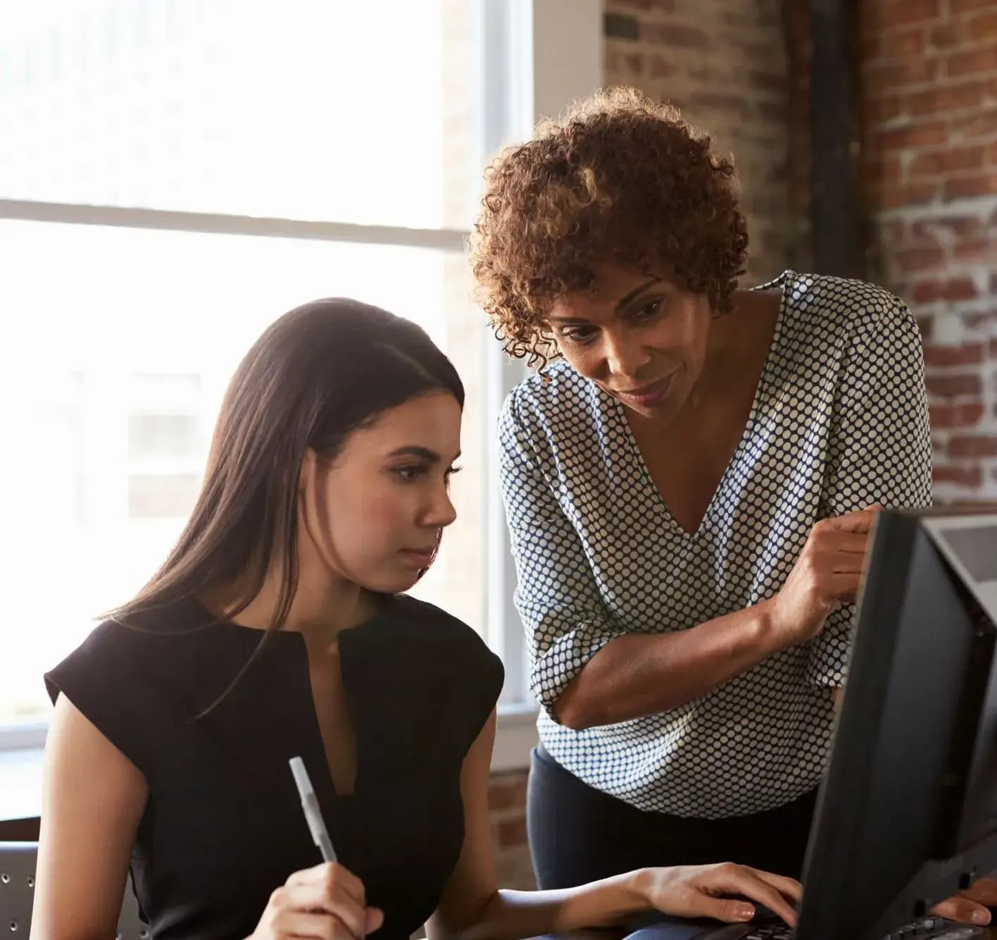 Two professional women collaborating at a computer